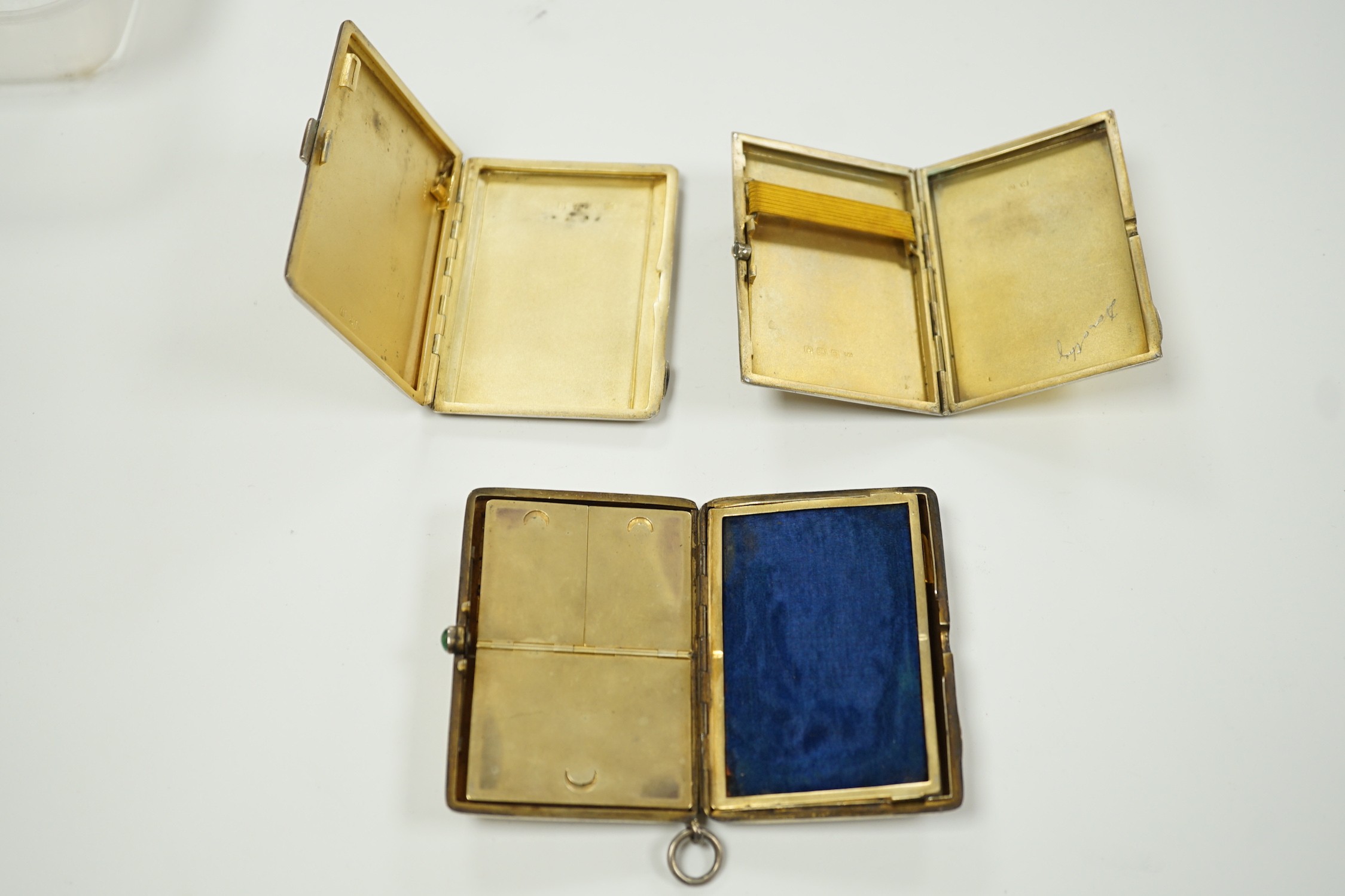 Two George V Art Deco silver and enamel cigarette cases, Birmingham, 1931 & 1932, largest 85mm (enamel a.f. on one) together with a German 800 standard white metal, cabochon emerald and rose cut diamond set compact/minau